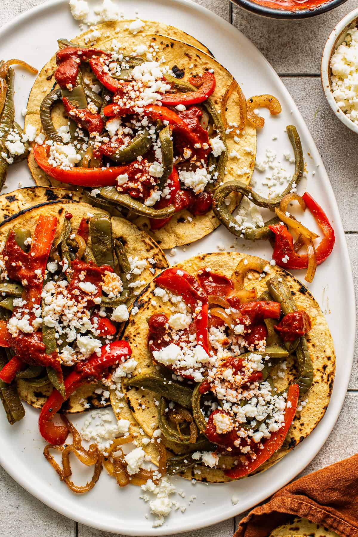 Three nopales tacos on a plate topped with guajillo salsa and cotija cheese.