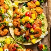Shrimp tostadas topped with avocado and mango pico de gallo.