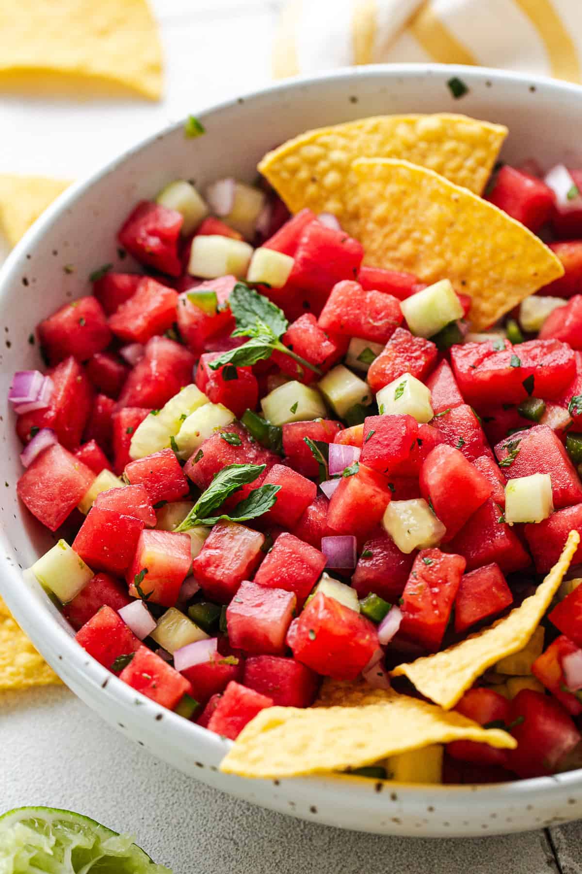 Watermelon salsa with mint and cucumber in a bowl served with tortilla chips.