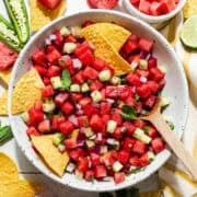 Watermelon salsa with mint and cucumber in a bowl with tortilla chips for eating.