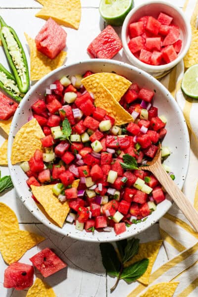 Watermelon salsa with mint and cucumber in a bowl with tortilla chips for eating.