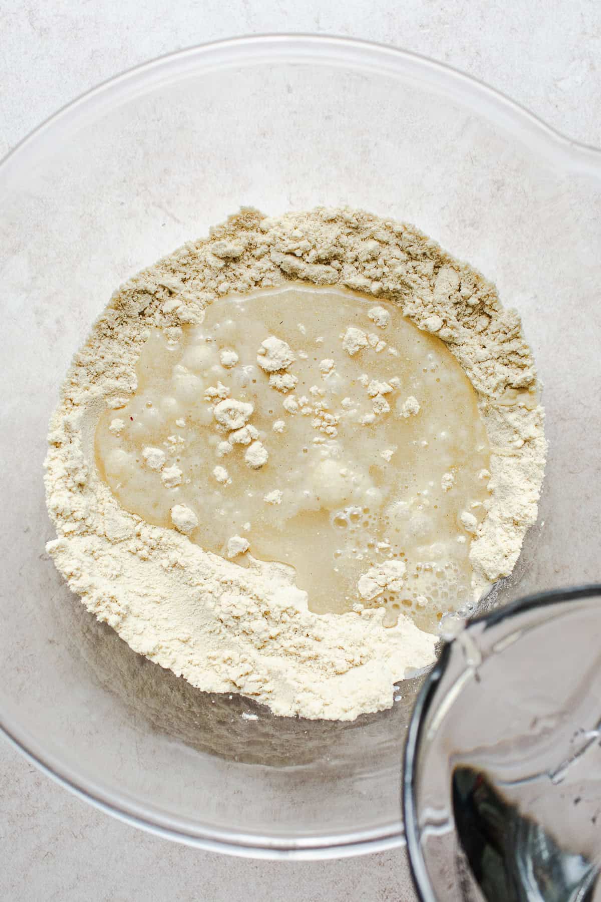 Warm water being poured into a bowl of masa harina and salt to make corn tortilla dough.