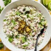 Mexican tuna salad (aka ensalada de atun) in a bowl topped with pickled jalapeño rings and served with tortilla chips.