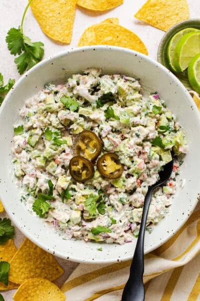 Mexican tuna salad (aka ensalada de atun) in a bowl topped with pickled jalapeño rings and served with tortilla chips.