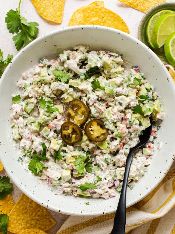 Mexican tuna salad (aka ensalada de atun) in a bowl topped with pickled jalapeño rings and served with tortilla chips.