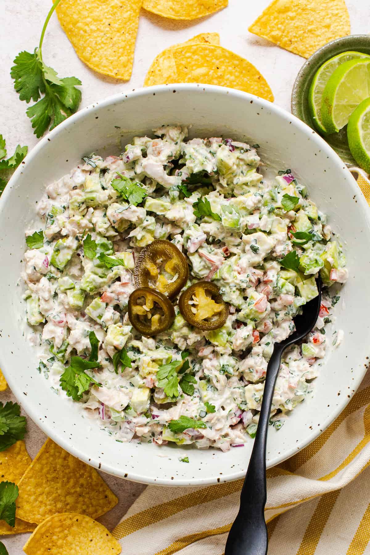 Mexican tuna salad (aka ensalada de atun) in a bowl topped with pickled jalapeño rings and served with tortilla chips.