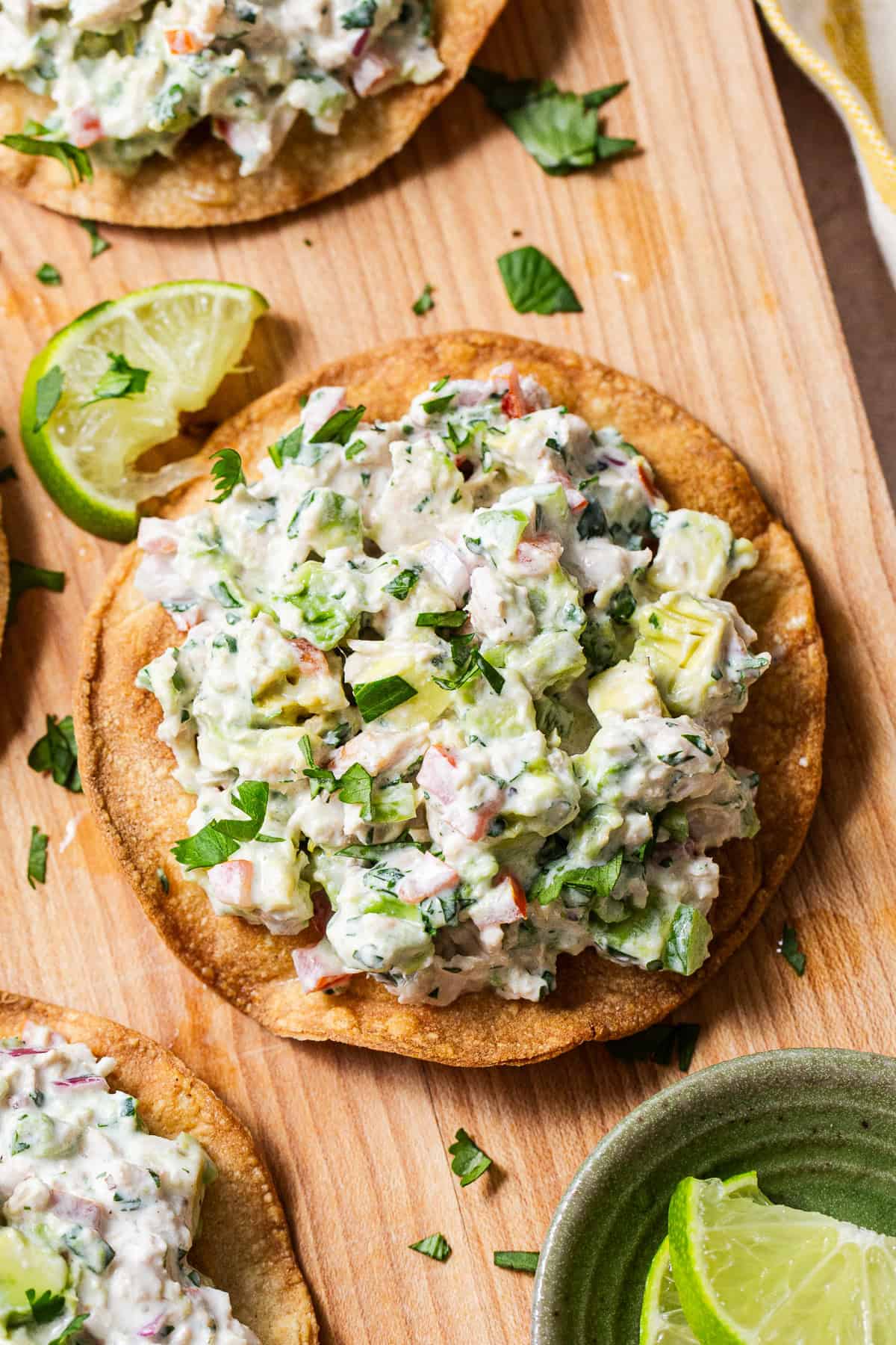 Mexican tuna salad piled onto tostadas on a cutting board.