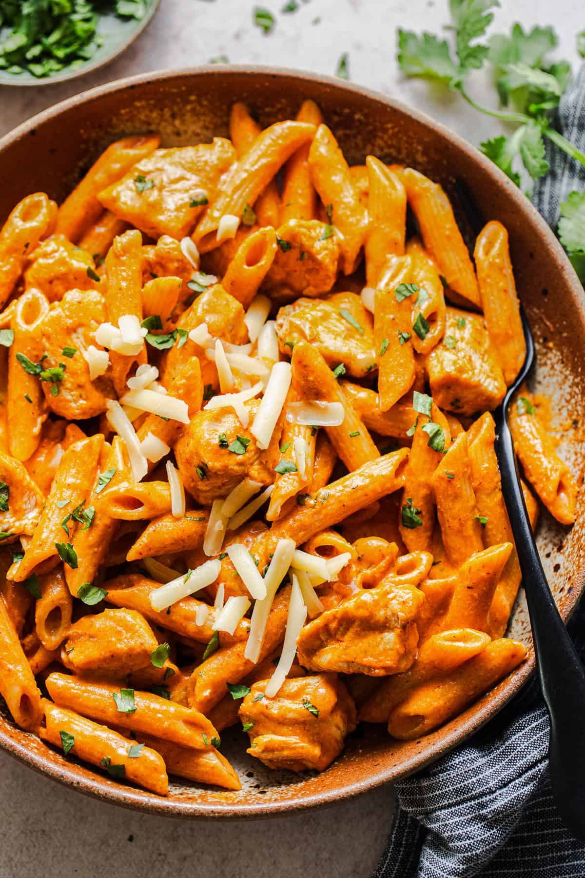 Creamy chipotle chicken pasta with penne, chicken, cilantro, and shredded cheese.