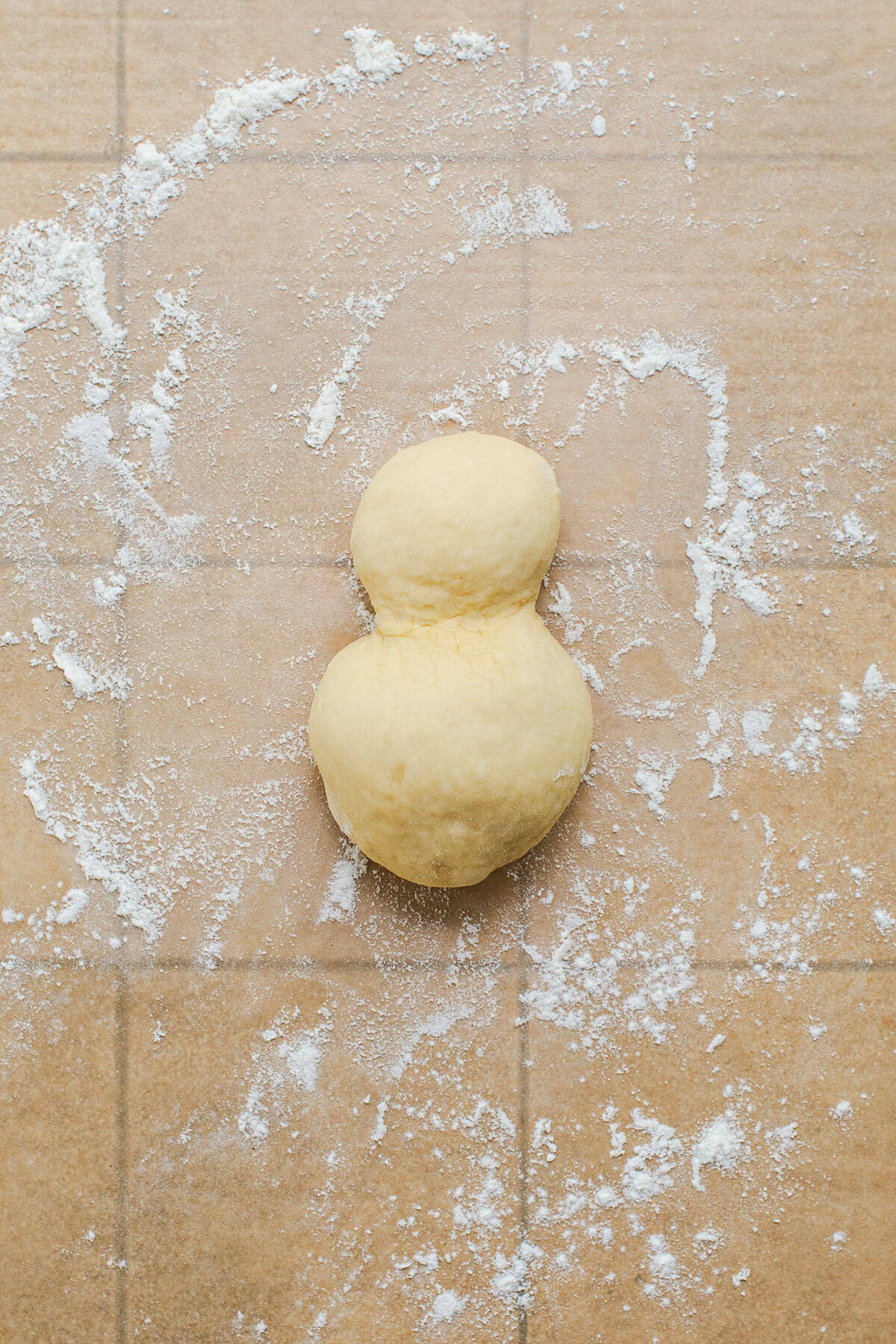 Cemita bun dough shaped into a snowman with a small ball joined to a bigger one.