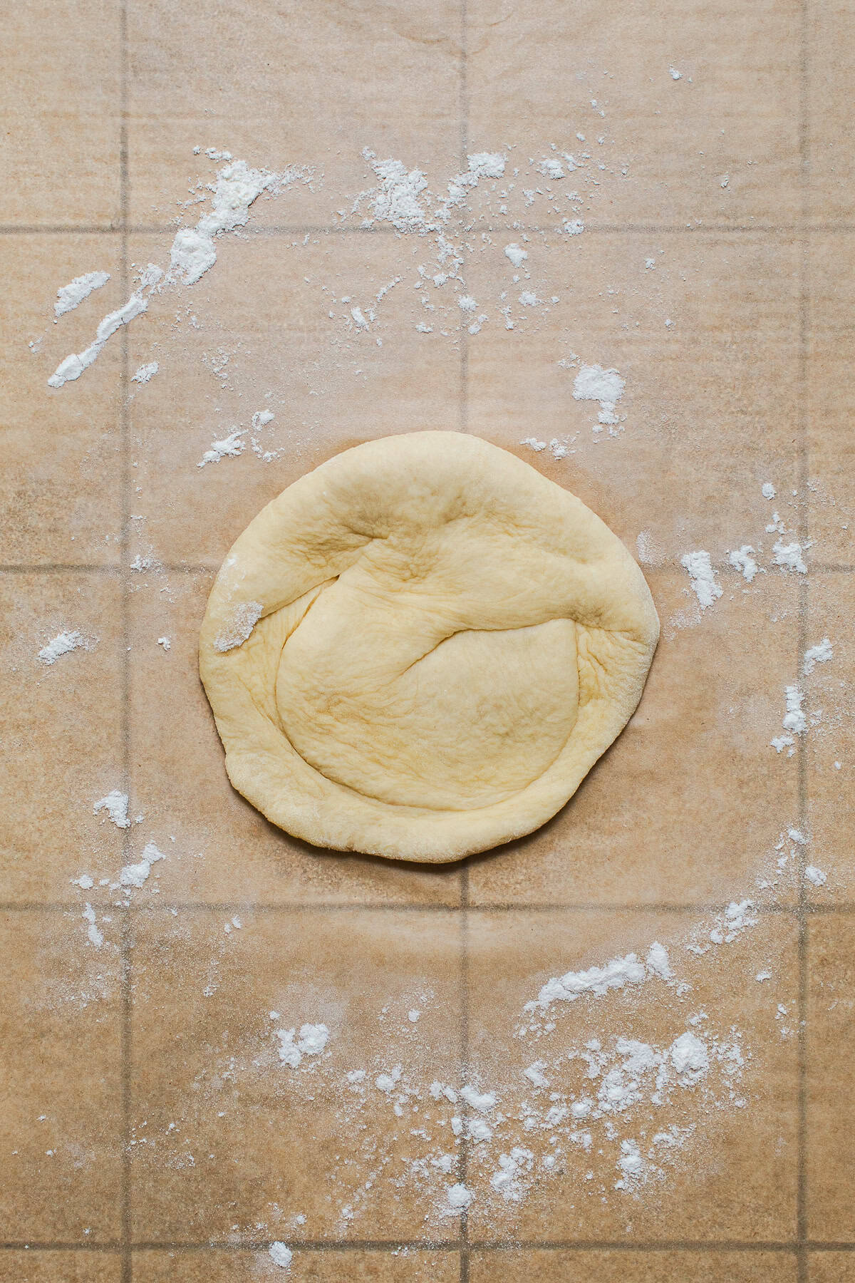 Cemita bun dough with the small end twisted and folded over, showing the curved ridge on top.