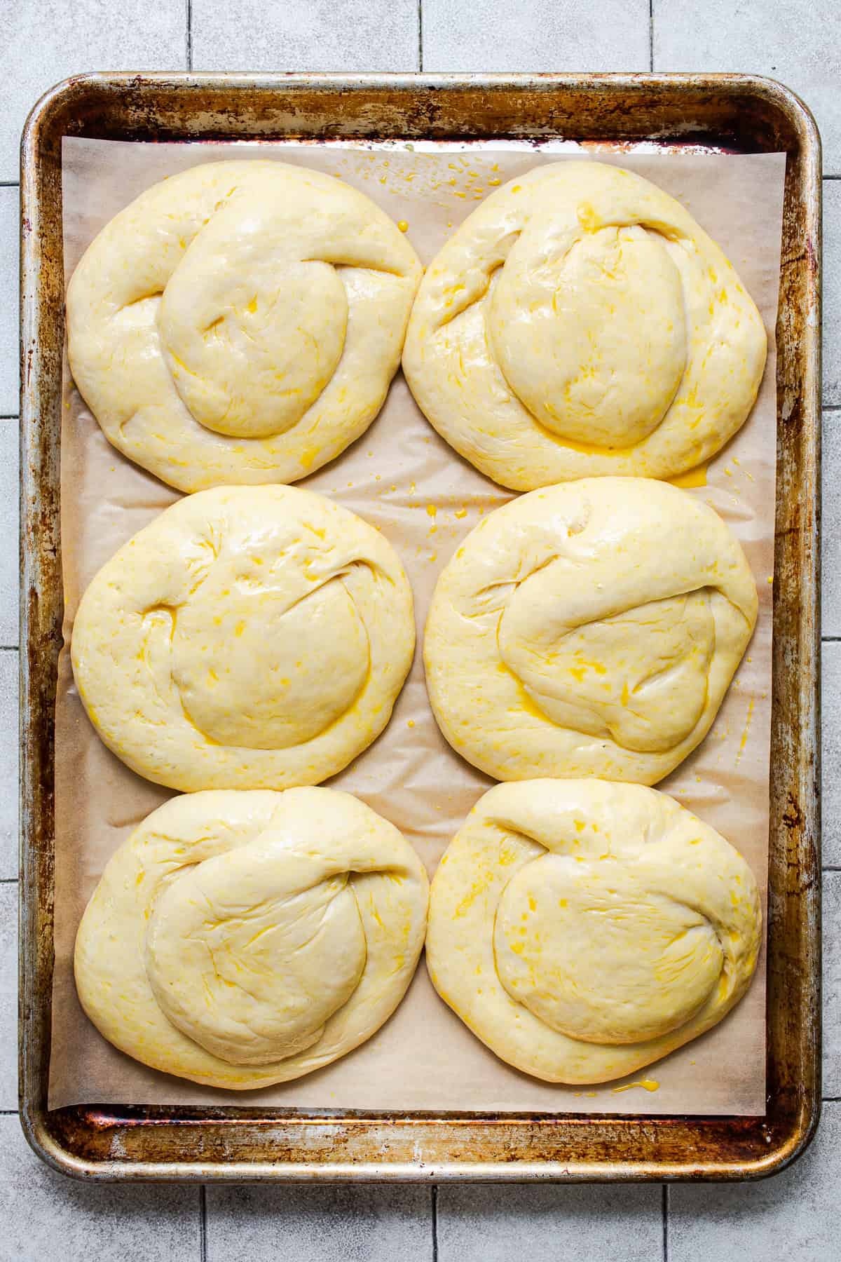Risen cemita buns brushed with egg wash and topped with sesame seeds.