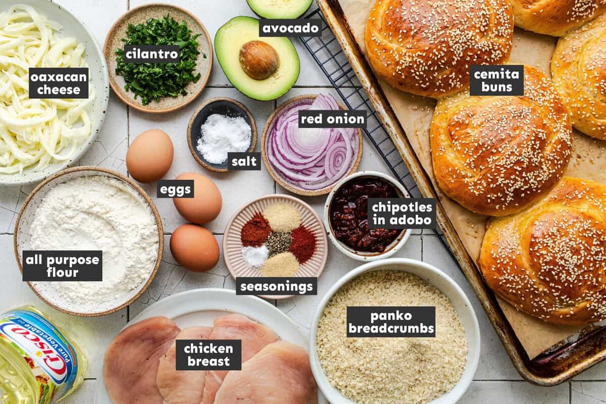 Ingredients for cemitas poblanas, including chicken breasts, panko, cemita buns, quesillo, avocado, chipotles, and onion.
