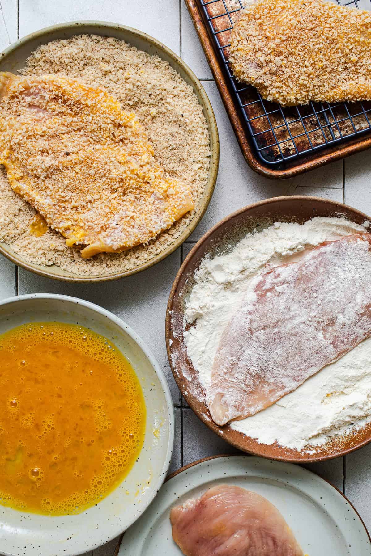 Chicken being breaded in flour, egg, and panko for milanesa.