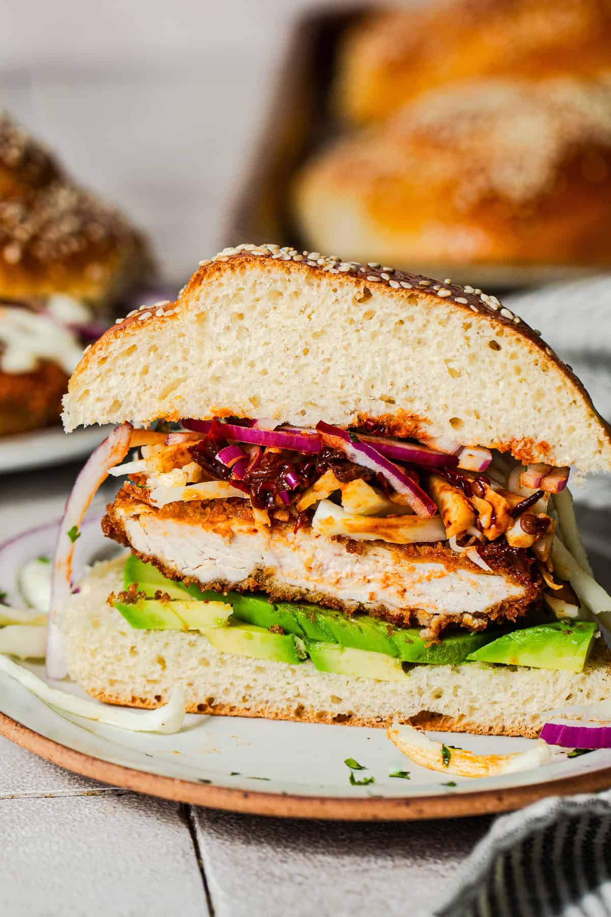 Cemitas poblanas sliced in half showing layers of milanesa, avocado, chipotles, and cheese.