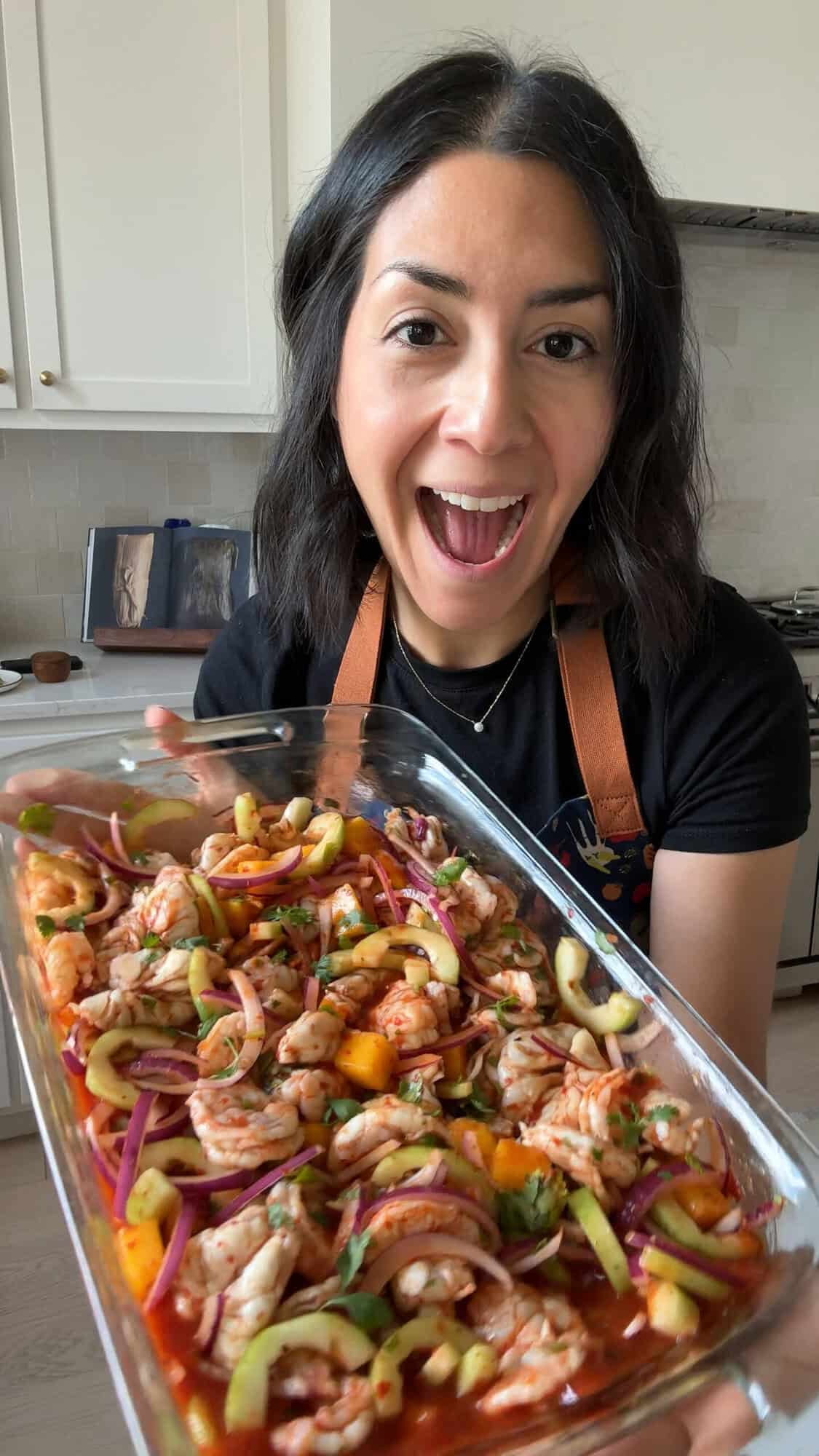 Isabel Orozco-Moore holding a dish of aguachile rojo in her kitchen.