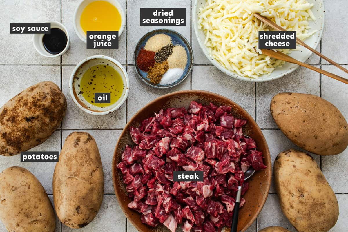 Ingredients for papas locas, including russet potatoes, steak, orange, soy sauce, and toppings.