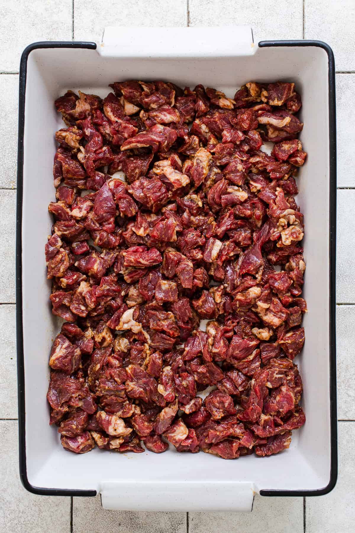 Steak marinating in a baking dish for papas locas carne asada.