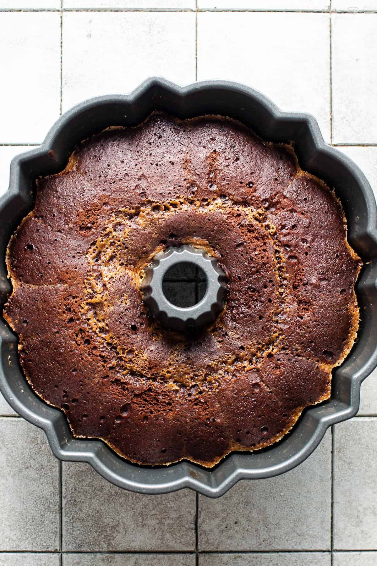 Baked pumpkin chocoflan cooling in a bundt pan with the foil removed.