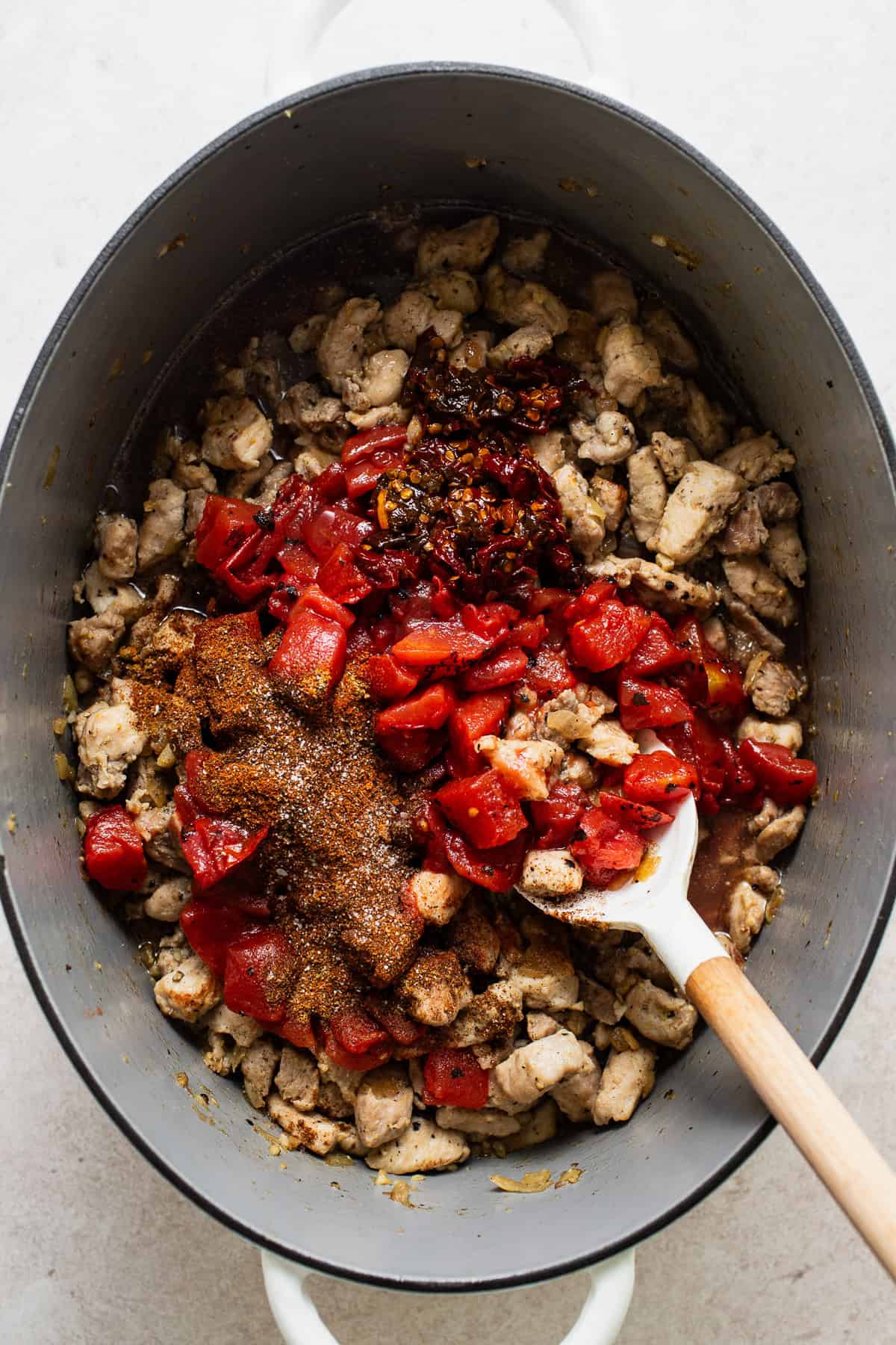 Tomatoes, chipotles, bean liquid, and spices added to the pork before the sweet potato chili simmers.