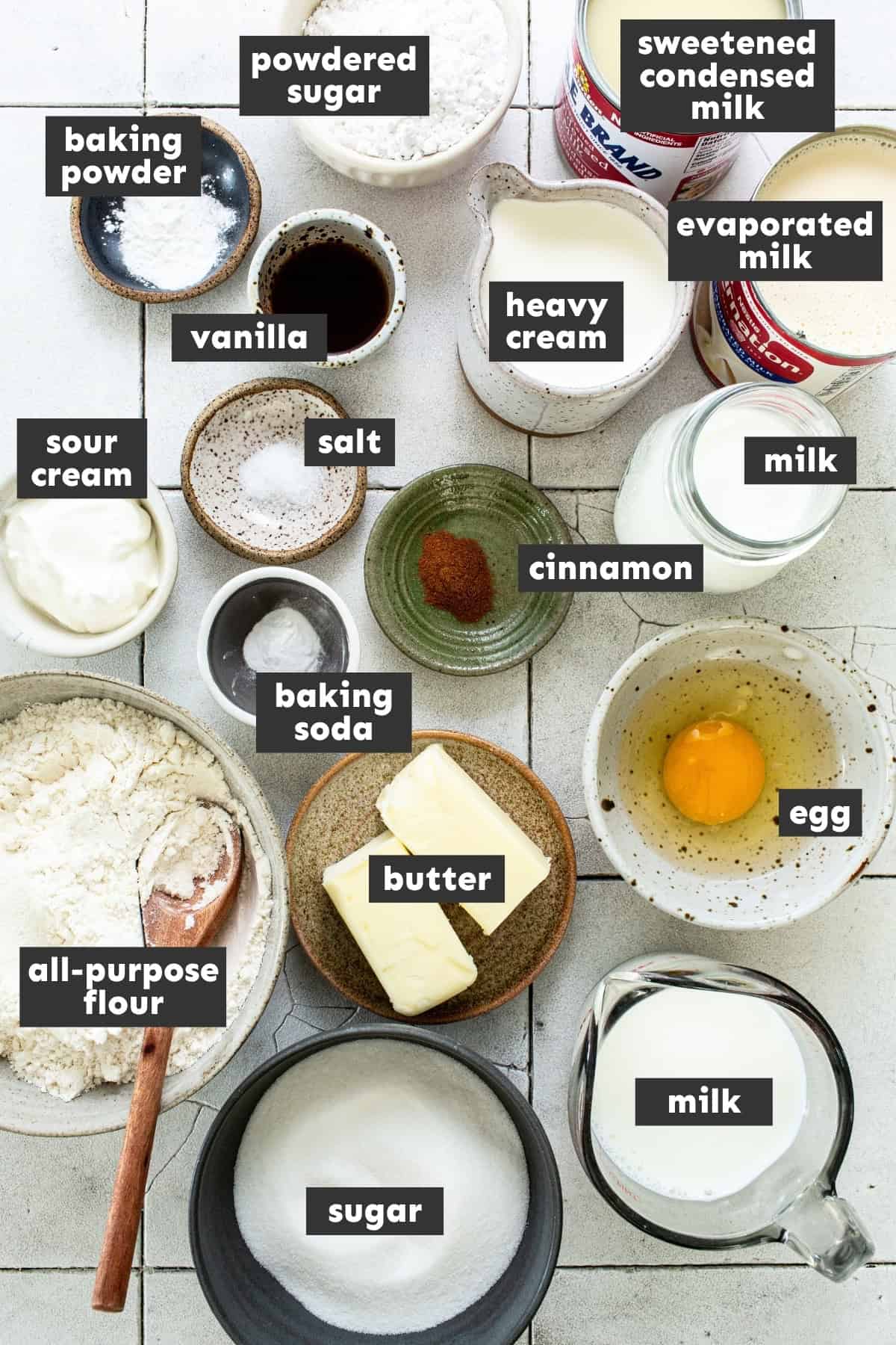 Ingredients for tres leches cupcakes, including cans of sweetened condensed milk and evaporated milk.